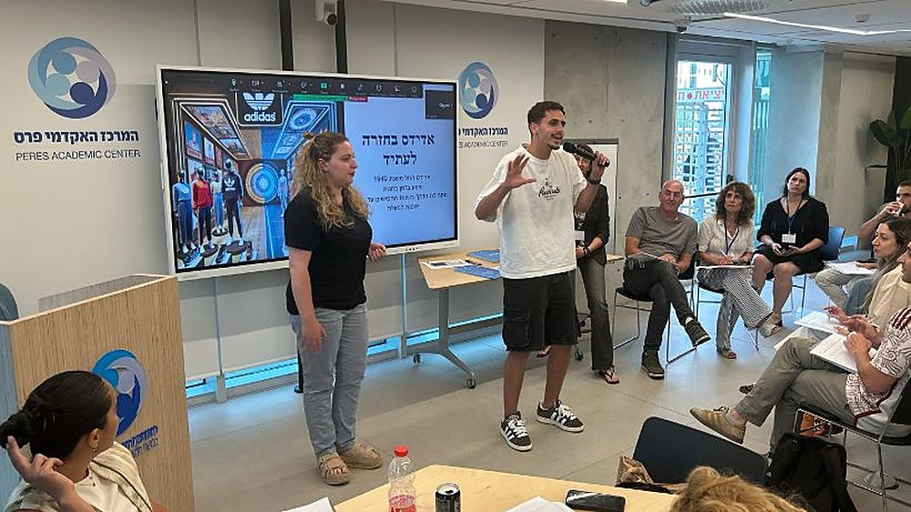 A workshop at the Peres Academic Center, with students seated around two speakers and a screen