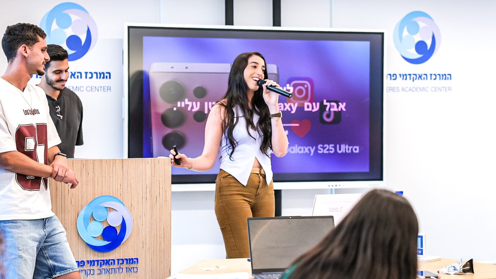 A student presenting to an audience with a microphone in front of a large screen