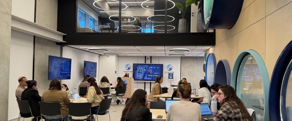 Students working at tables in a modern open study center at the Peres Academic Center