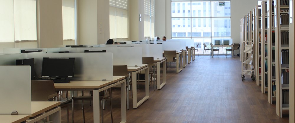 The library at the Peres Academic Center, with study desks along one side and book stacks along the other